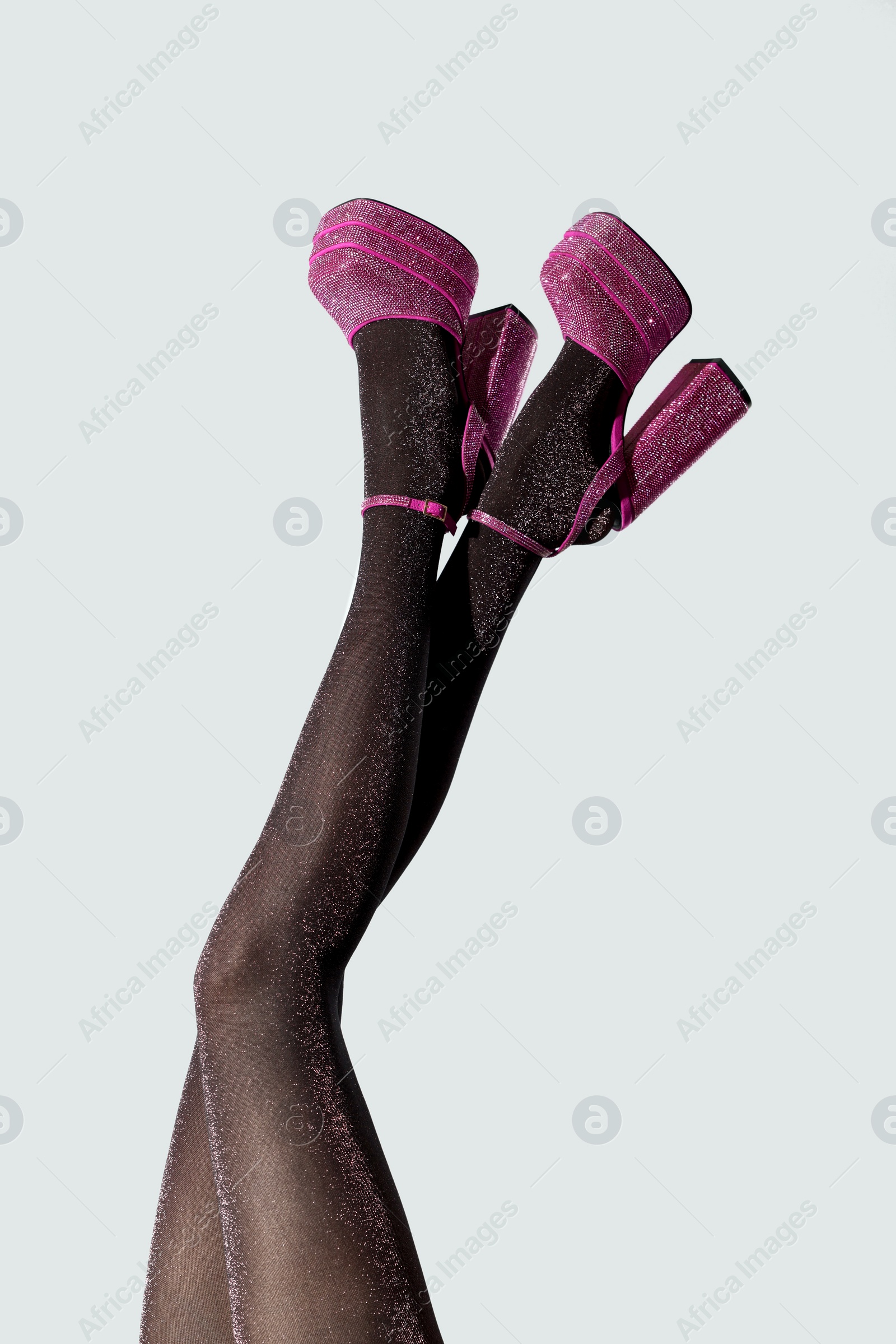 Photo of Woman wearing pink high heeled shoes with platform and square toes on light grey background, closeup