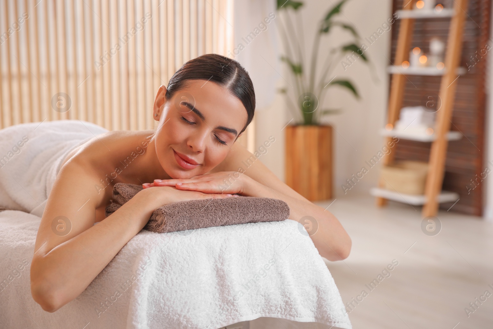 Photo of Young woman resting on massage couch in spa salon, space for text