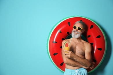Photo of Shirtless man with inflatable ring and glass of cocktail on color background