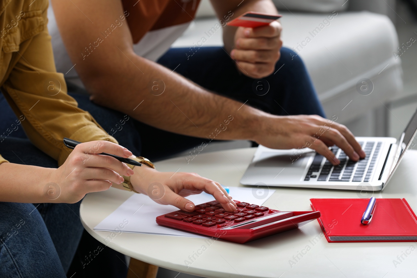 Photo of Young couple discussing family budget at table indoors, closeup