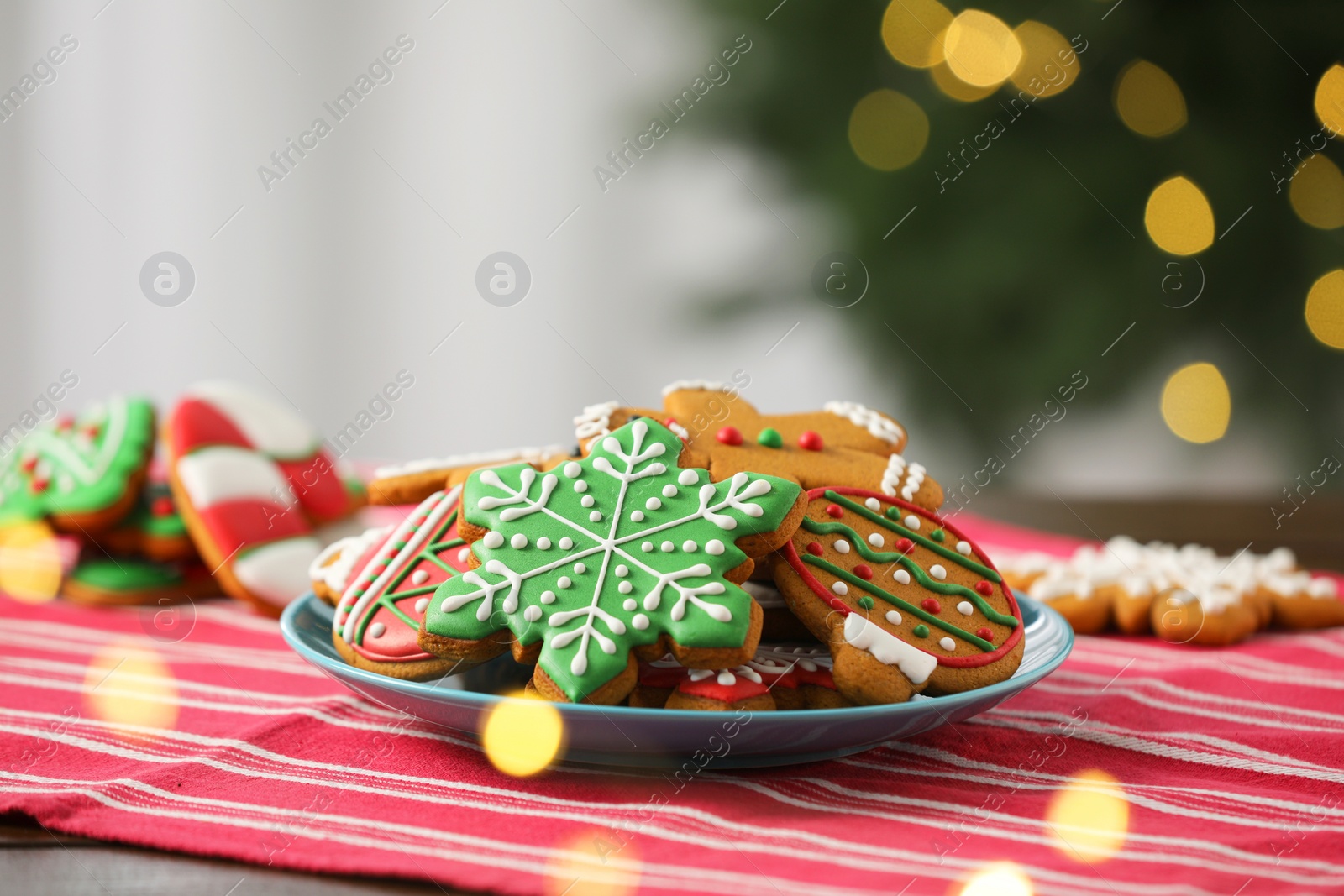 Photo of Decorated cookies on table against blurred Christmas lights