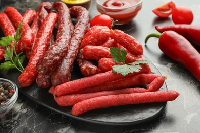 Thin dry smoked sausages served on black marble table, closeup