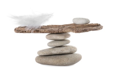 Photo of Stack of stones with tree branch and feather on white background. Balance concept
