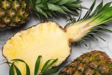 Photo of Whole and cut ripe pineapples on white marble table, flat lay