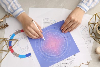 Astrologer using zodiac wheel for fate forecast at table, top view. Fortune telling