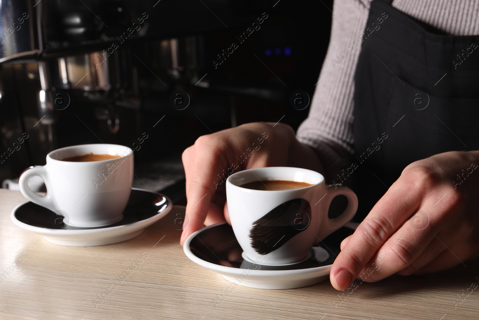 Photo of Barista with cup of fresh aromatic coffee at wooden counter in cafe, closeup