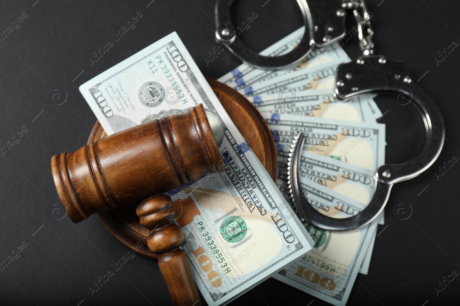 Photo of Law gavel, dollars and handcuffs on grey table, flat lay