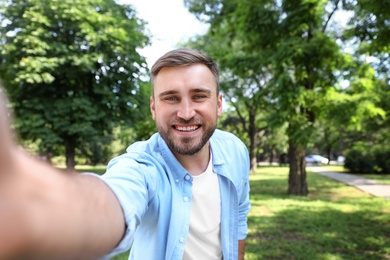 Photo of Happy young man taking selfie in park