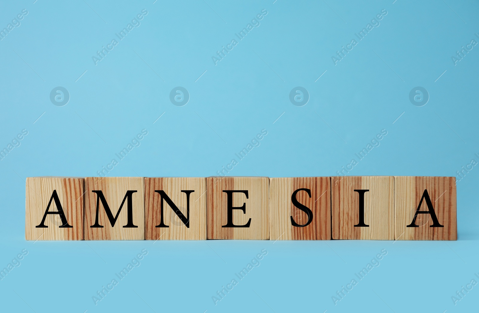 Photo of Wooden cubes with word Amnesia on light blue background