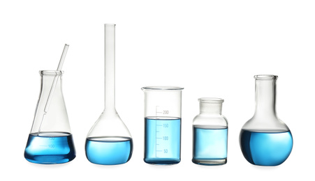 Photo of Different laboratory glassware with light blue liquid isolated on white