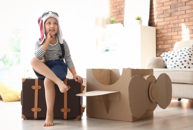 Adorable little child playing with cardboard plane at home