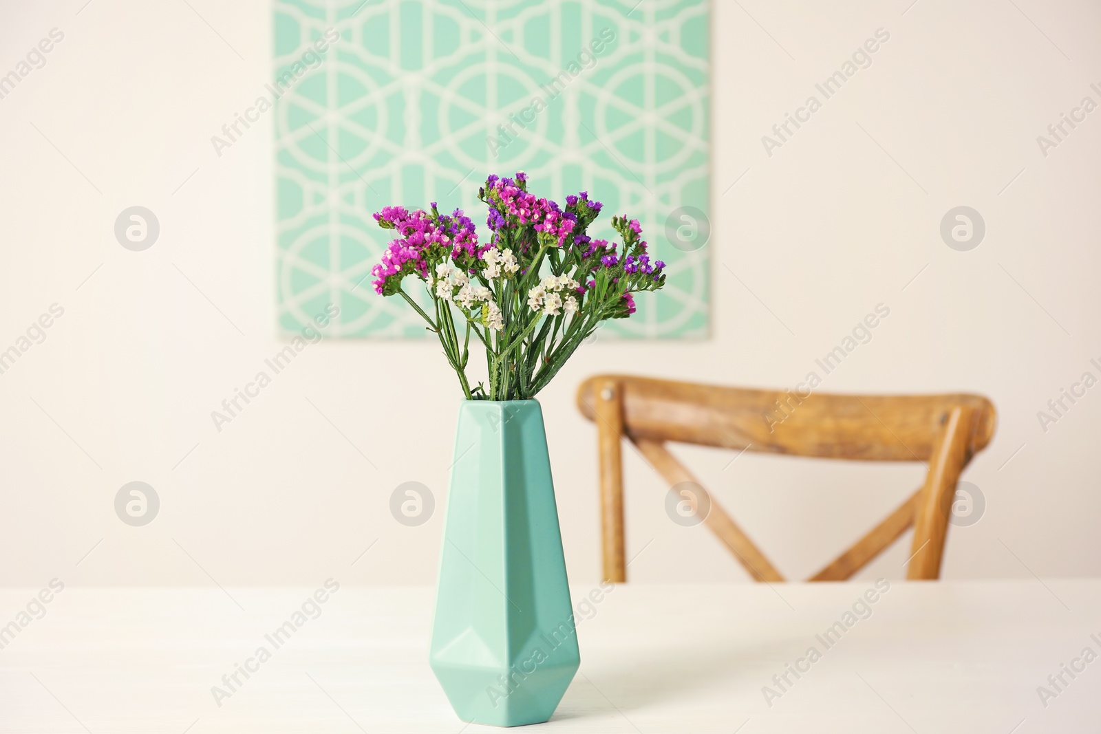 Photo of Beautiful flowers in vase and space for text on blurred background. Element of interior design