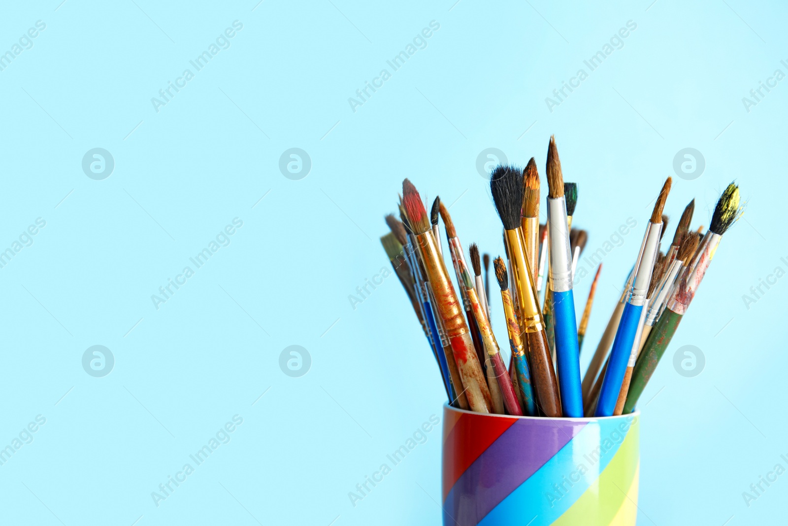 Photo of Holder with paint brushes on color background. Space for text