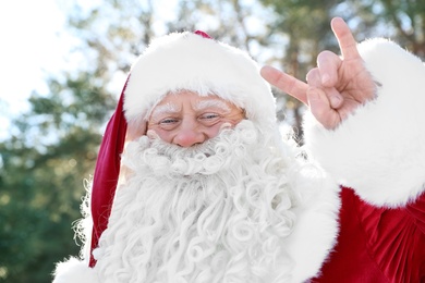 Photo of Happy Authentic Santa Claus showing rock gesture outdoors