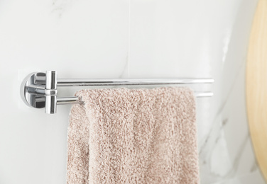 Photo of Holder with clean towel on light wall in bathroom