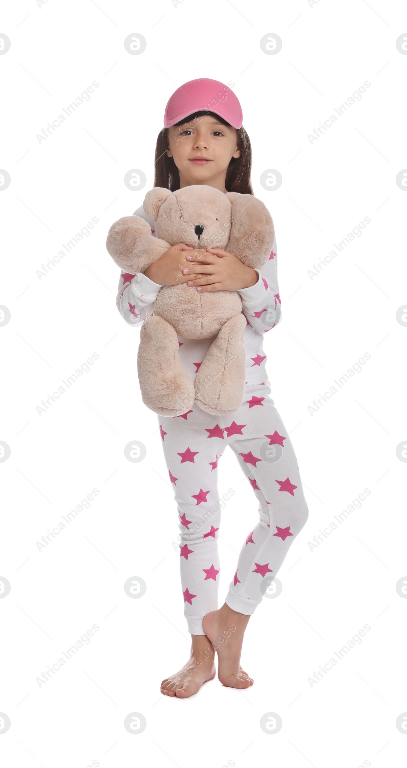 Photo of Cute girl wearing pajamas and sleeping mask with teddy bear on white background