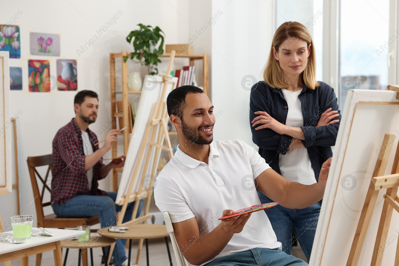 Photo of Artist and her students having painting class in studio. Creative hobby