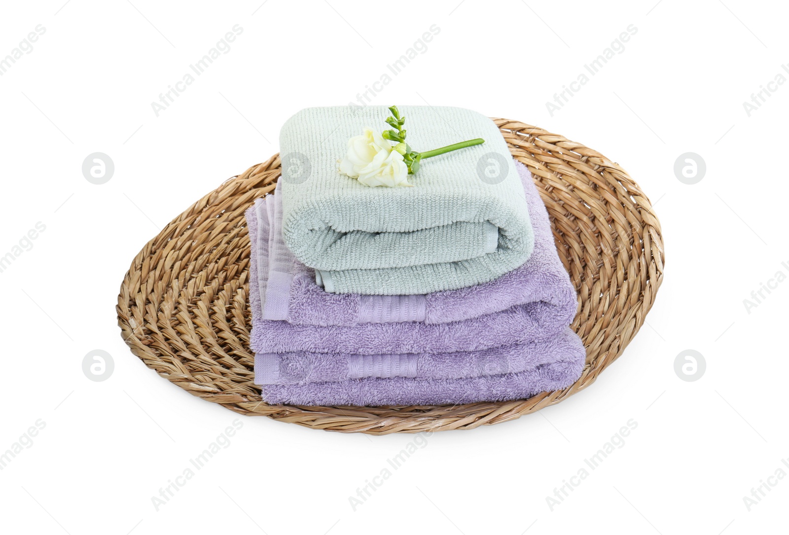 Photo of Different folded soft towels and freesia flower isolated on white