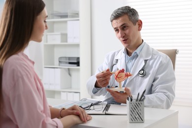 Photo of Gastroenterologist with human stomach model consulting patient at table in clinic