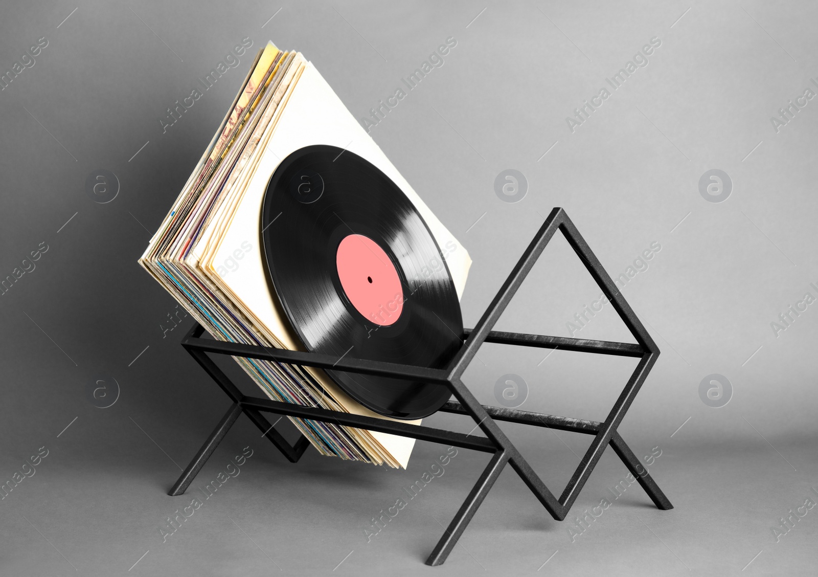 Photo of Rack with vinyl records in sleeves on grey background