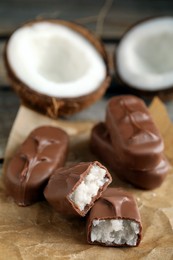 Delicious milk chocolate candy bars with coconut filling on table, closeup