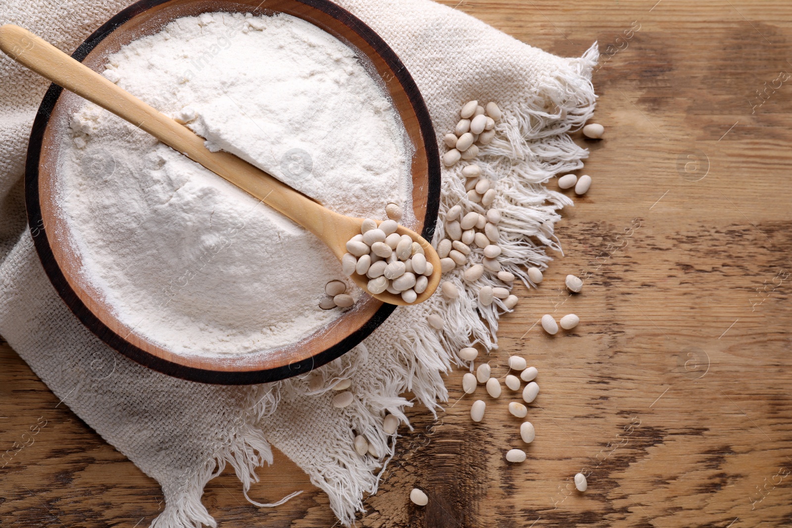 Photo of Kidney bean flour and seeds on wooden table, flat lay. Space for text