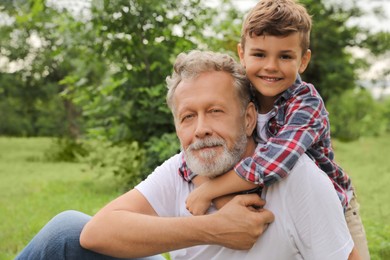 Cute little boy and grandfather spending time together in park