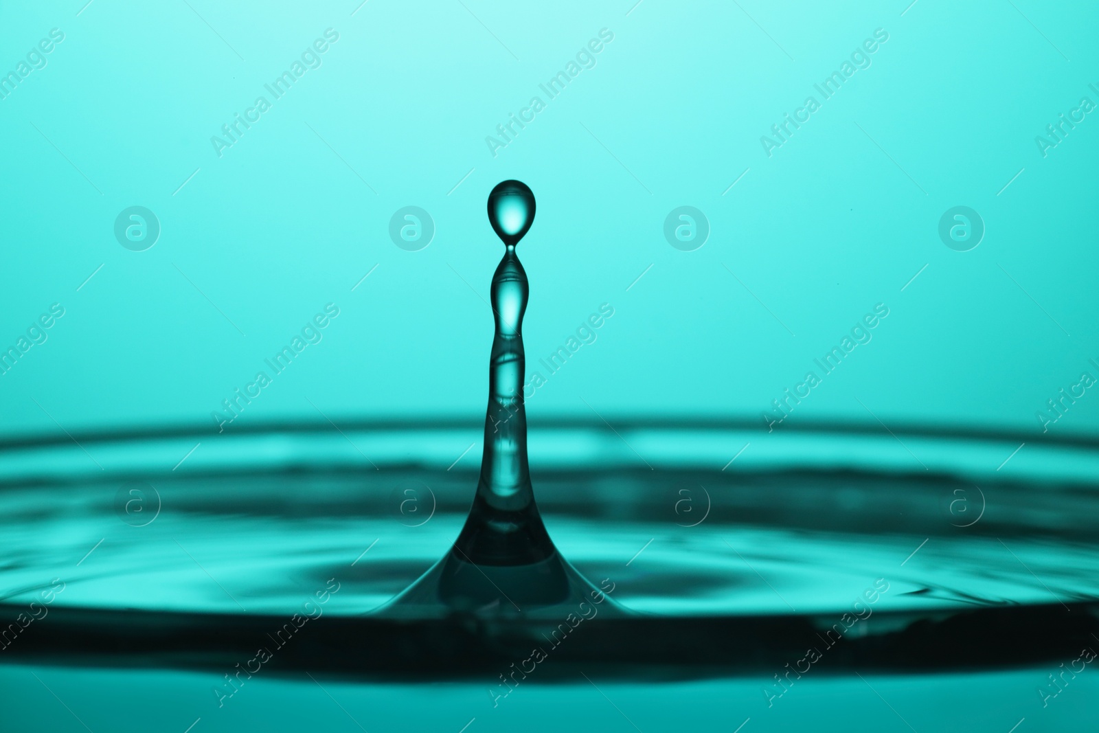 Photo of Splash of clear water with drops on turquoise background, closeup