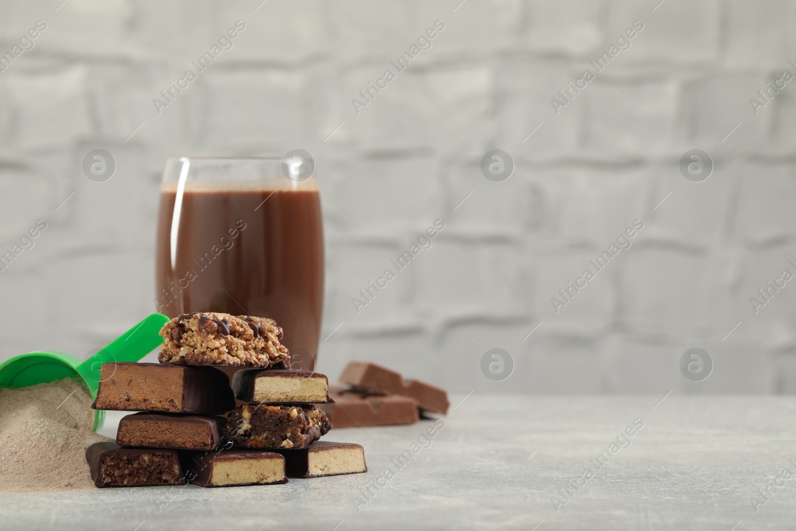 Photo of Different energy bars, protein cocktail and powder on grey table. Space for text