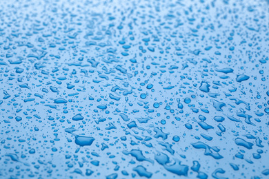 Water drops on light blue background, closeup view