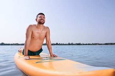 Photo of Man practicing yoga on SUP board on river