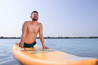 Man practicing yoga on SUP board on river