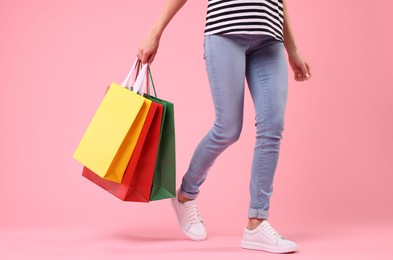 Woman with shopping bags on pink background, closeup