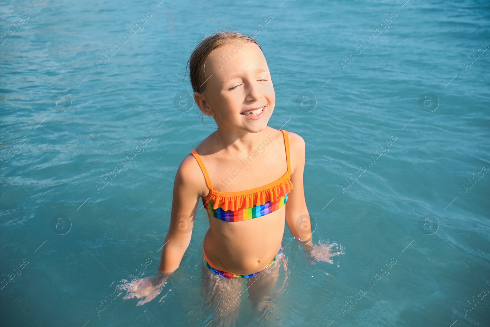 Photo of Happy little girl in sea on sunny day. Beach holiday