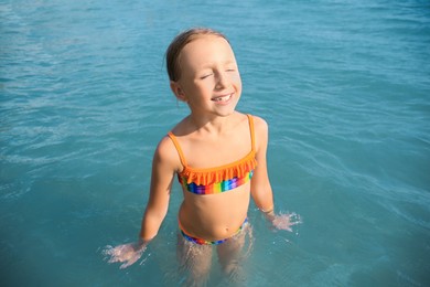 Photo of Happy little girl in sea on sunny day. Beach holiday