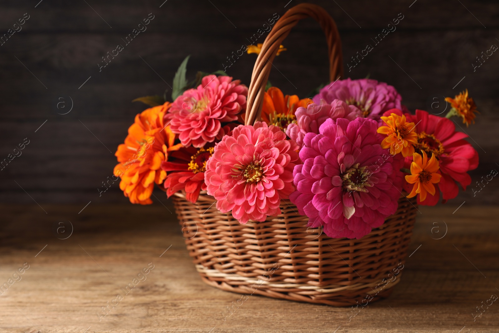 Photo of Beautiful wild flowers in wicker basket on wooden table