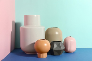 Photo of Stylish empty ceramic vases on color background