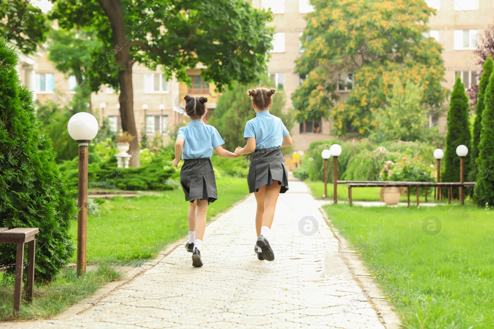 Photo of Little girls in stylish school uniform outdoors