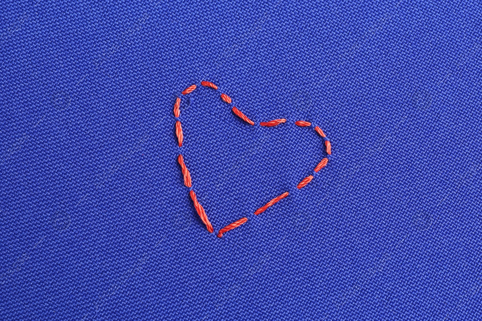 Photo of Embroidered heart on blue cloth, top view