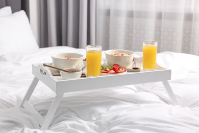Photo of Tray with tasty breakfast on bed at home
