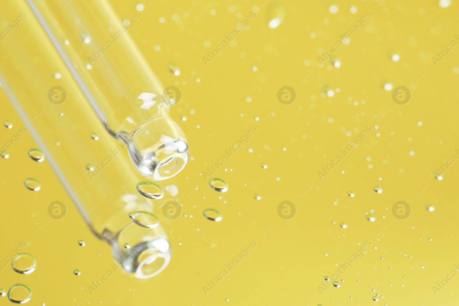 Photo of Pipette near serum drops on beautiful mirror, closeup with space for text. Toned in yellow