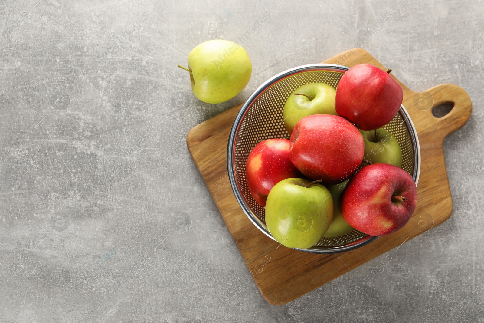 Photo of Fresh ripe apples in colander on light grey table, top view. Space for text