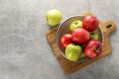 Fresh ripe apples in colander on light grey table, top view. Space for text