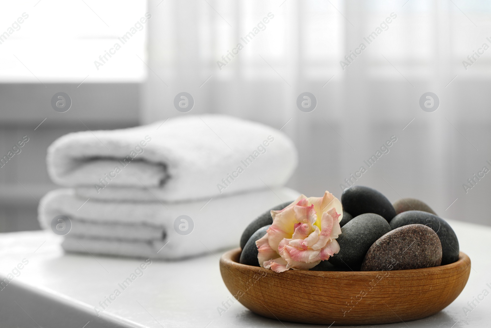 Photo of Spa stones and flowers on white table indoors