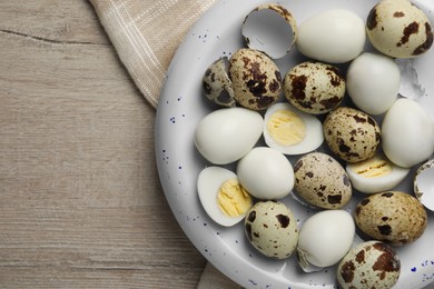 Unpeeled and peeled hard boiled quail eggs in bowl on white wooden table, top view. Space for text