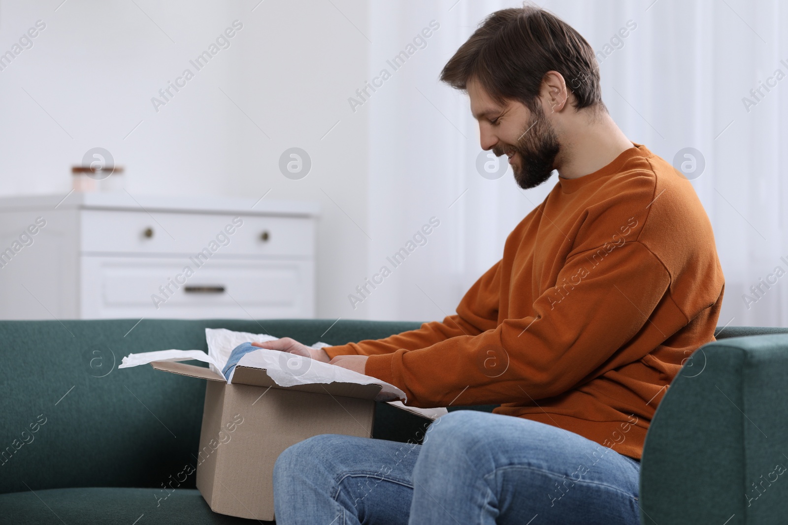 Photo of Happy man opening parcel at home. Internet shopping