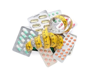 Photo of Many different weight loss pills and measuring tape on white background, top view