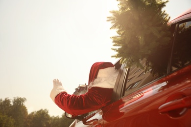Photo of Authentic Santa Claus with fir tree driving modern car, back view