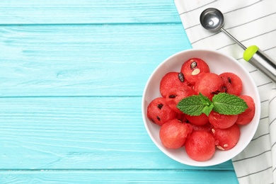 Bowl of watermelon balls with mint on light blue wooden table, flat lay. Space for text