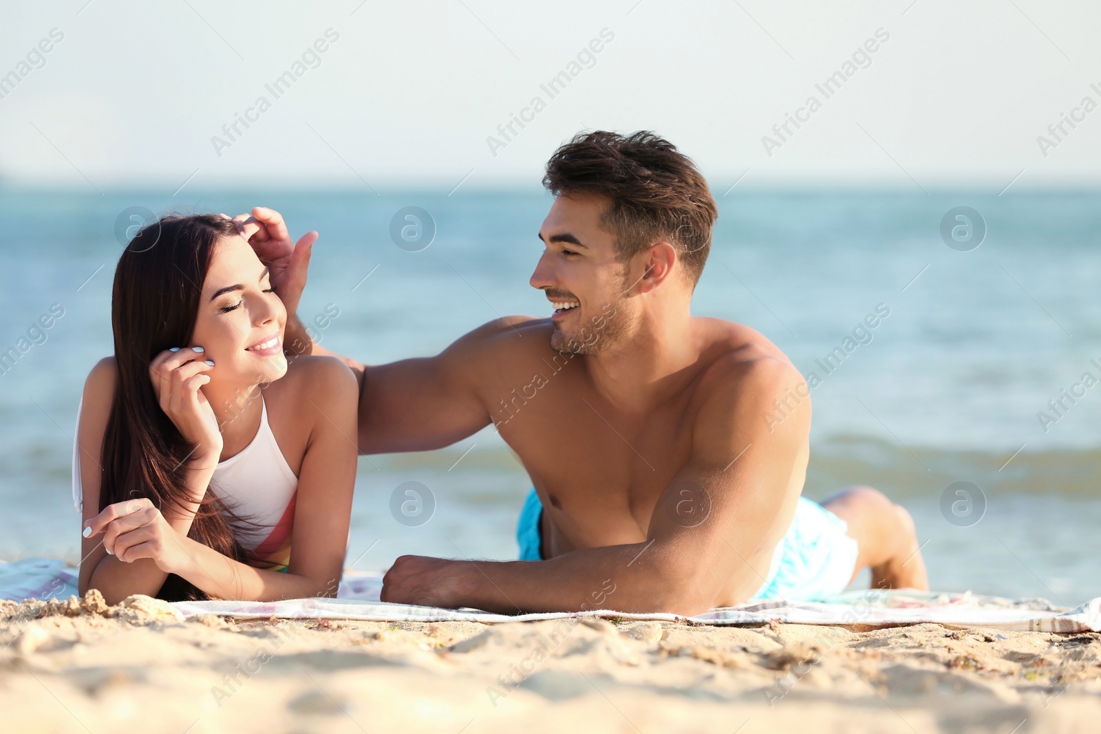 Photo of Happy young couple lying together on beach